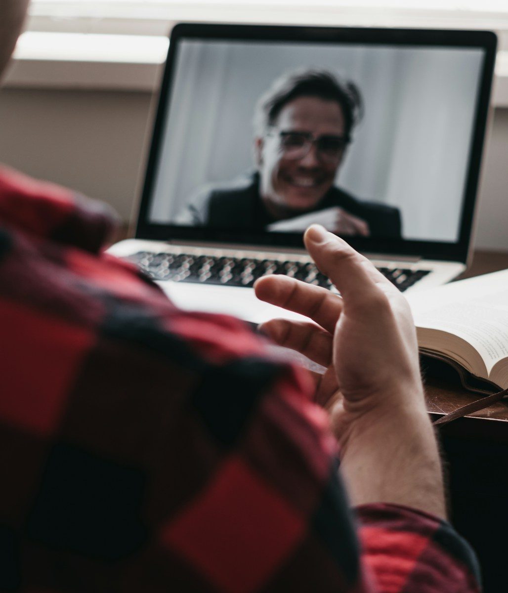 person in red and black plaid long sleeve shirt using black laptop computer